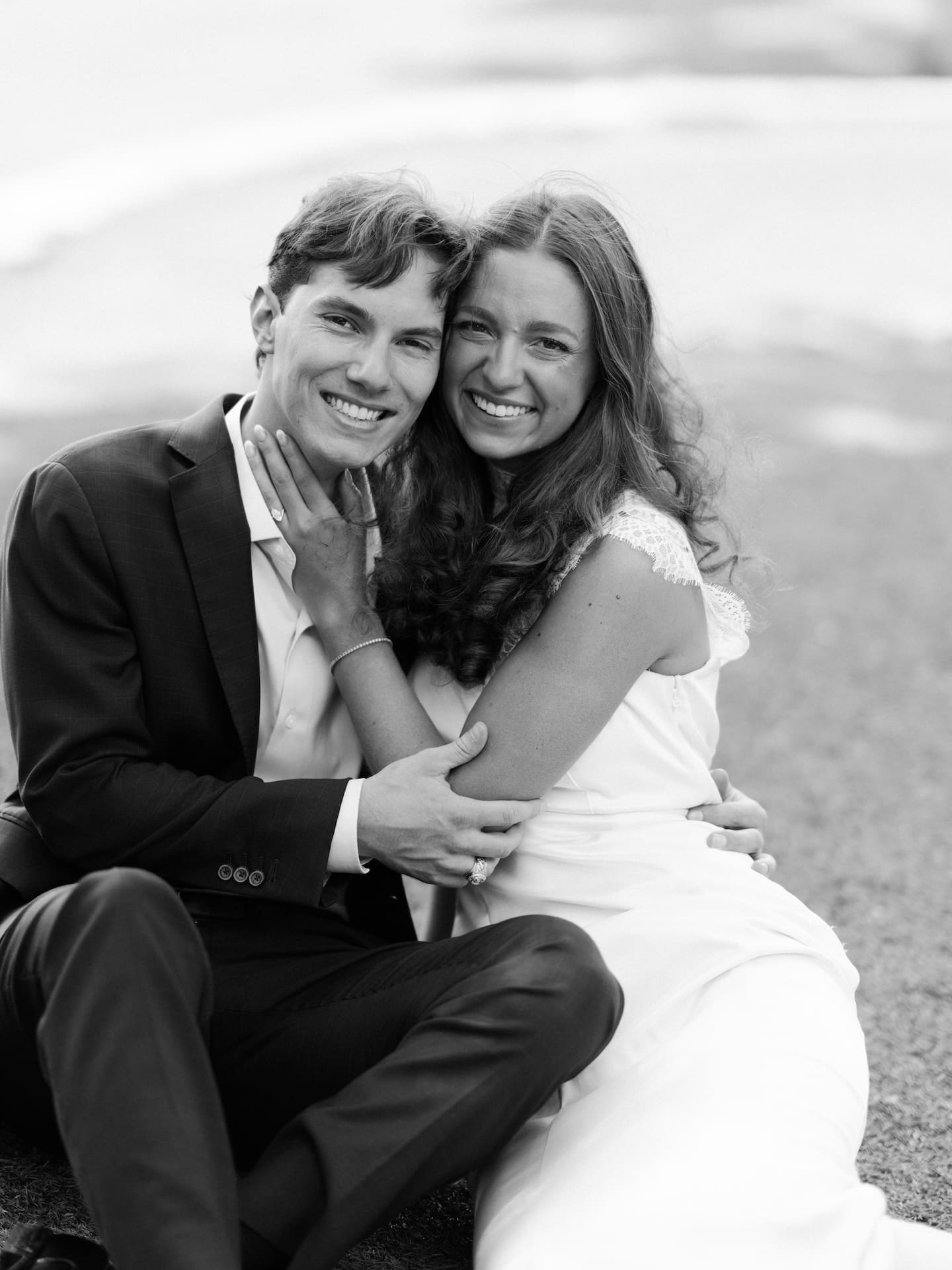 Fall engagement photos of a couple sitting closely, smiling for the camera in black and white.