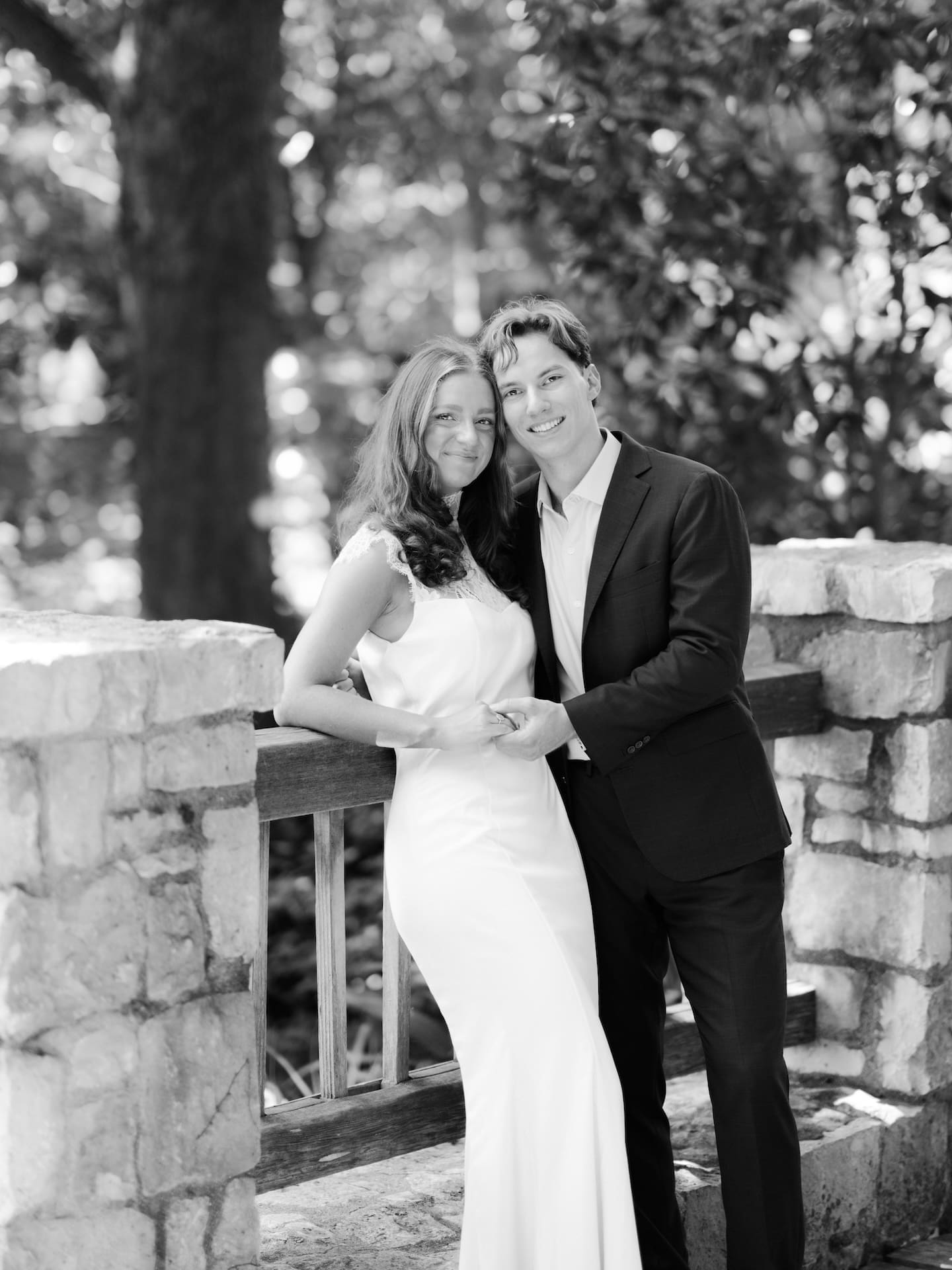Fall engagement photos of a couple smiling together on a stone bridge in black and white.