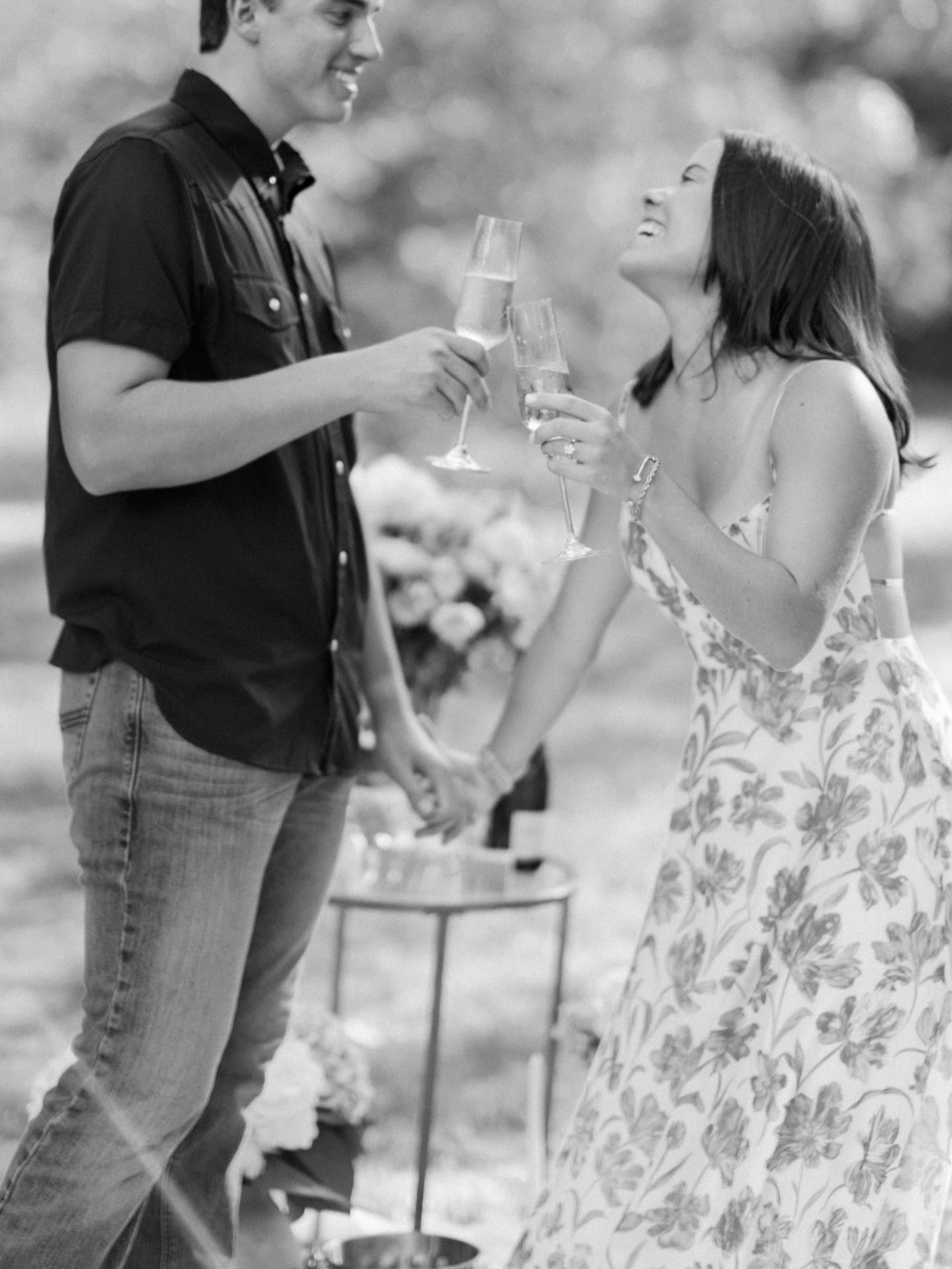 Surprise Engagement Proposal Ideas captured in black and white as a couple toasts champagne glasses.