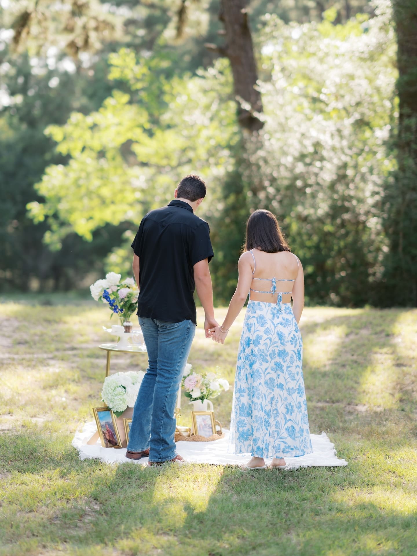 Surprise Engagement Proposal Ideas featuring a couple walking hand in hand away from their picnic setup.