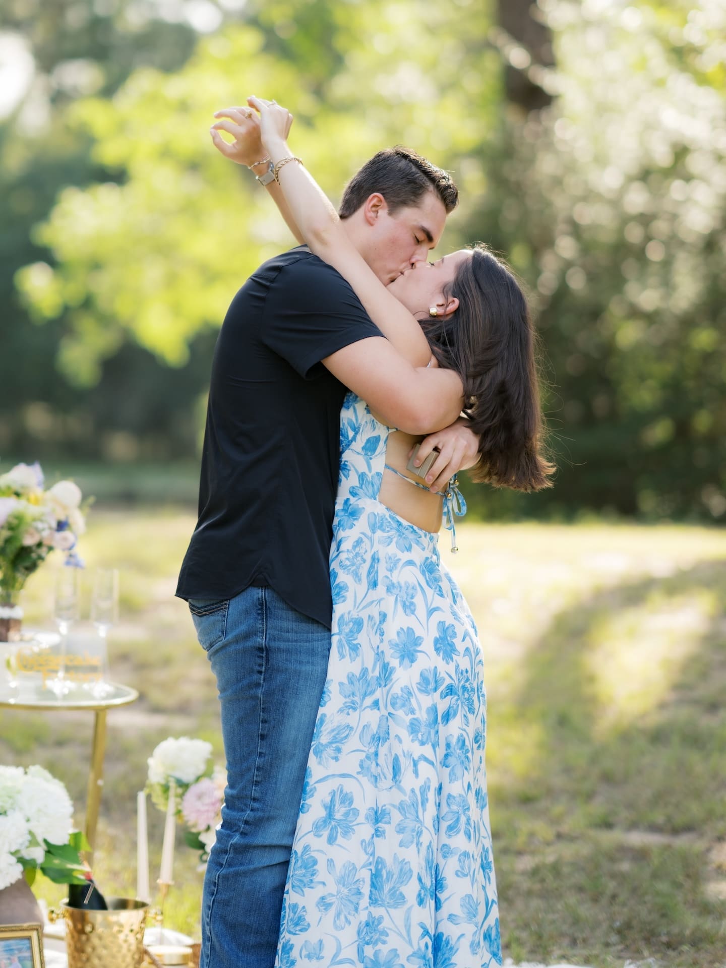 Surprise Engagement Proposal Ideas showing a couple sharing a kiss beside their picnic setup.