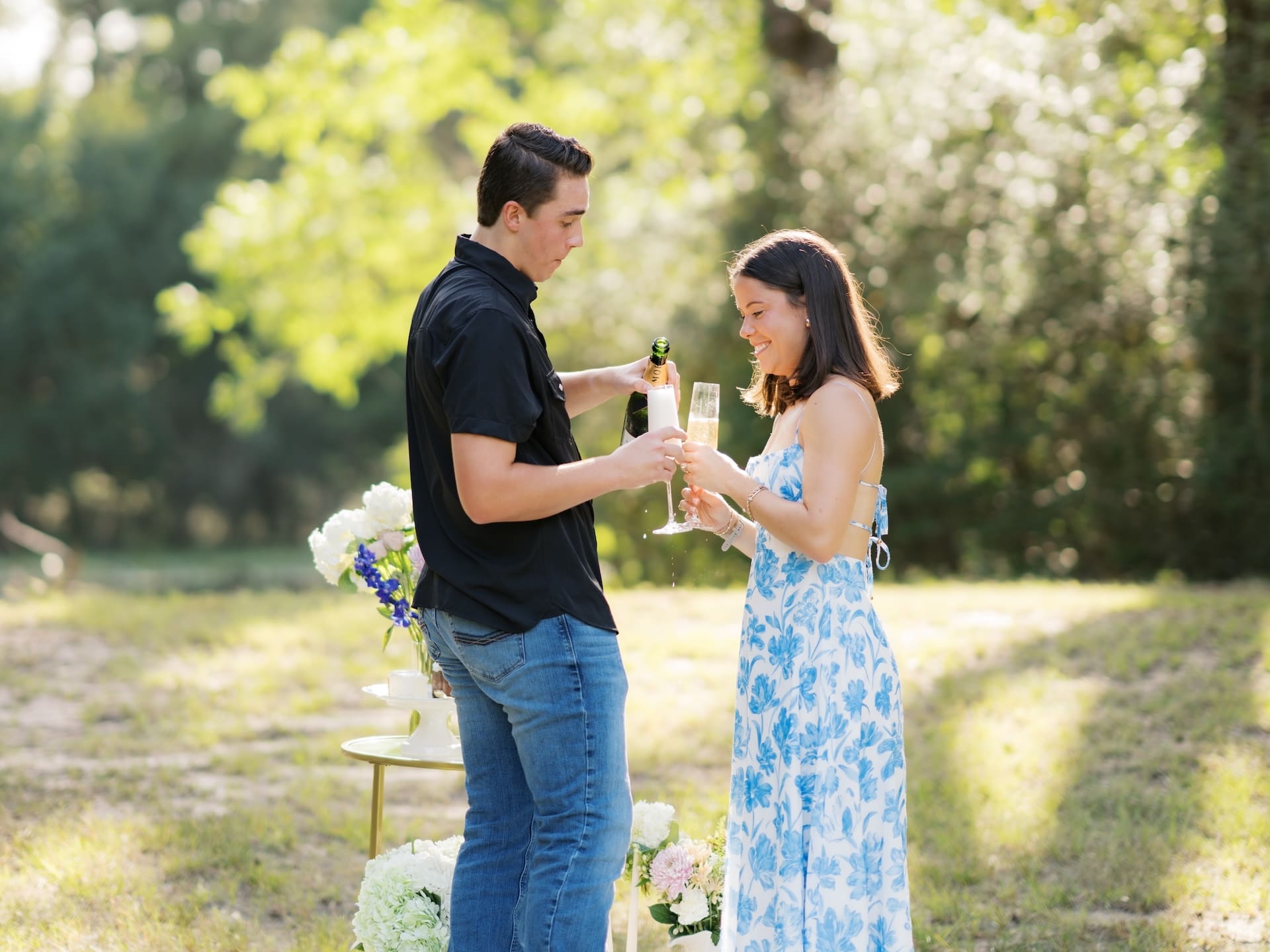 Surprise Engagement Proposal Ideas with a couple toasting champagne after getting engaged outdoors.