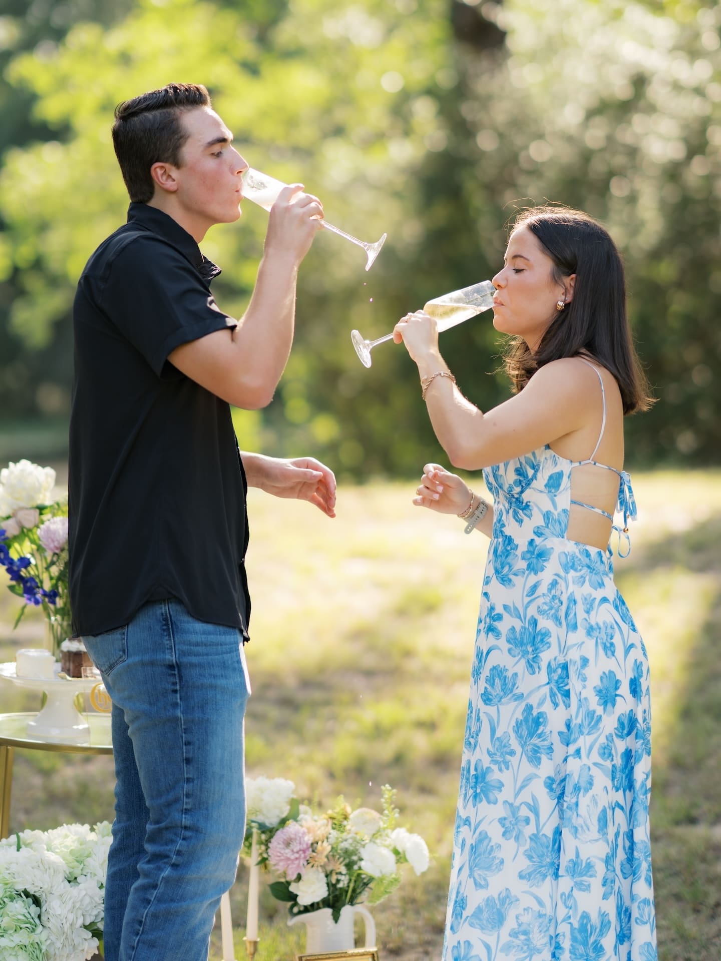 Newly engaged couple sipping champagne together outdoors.