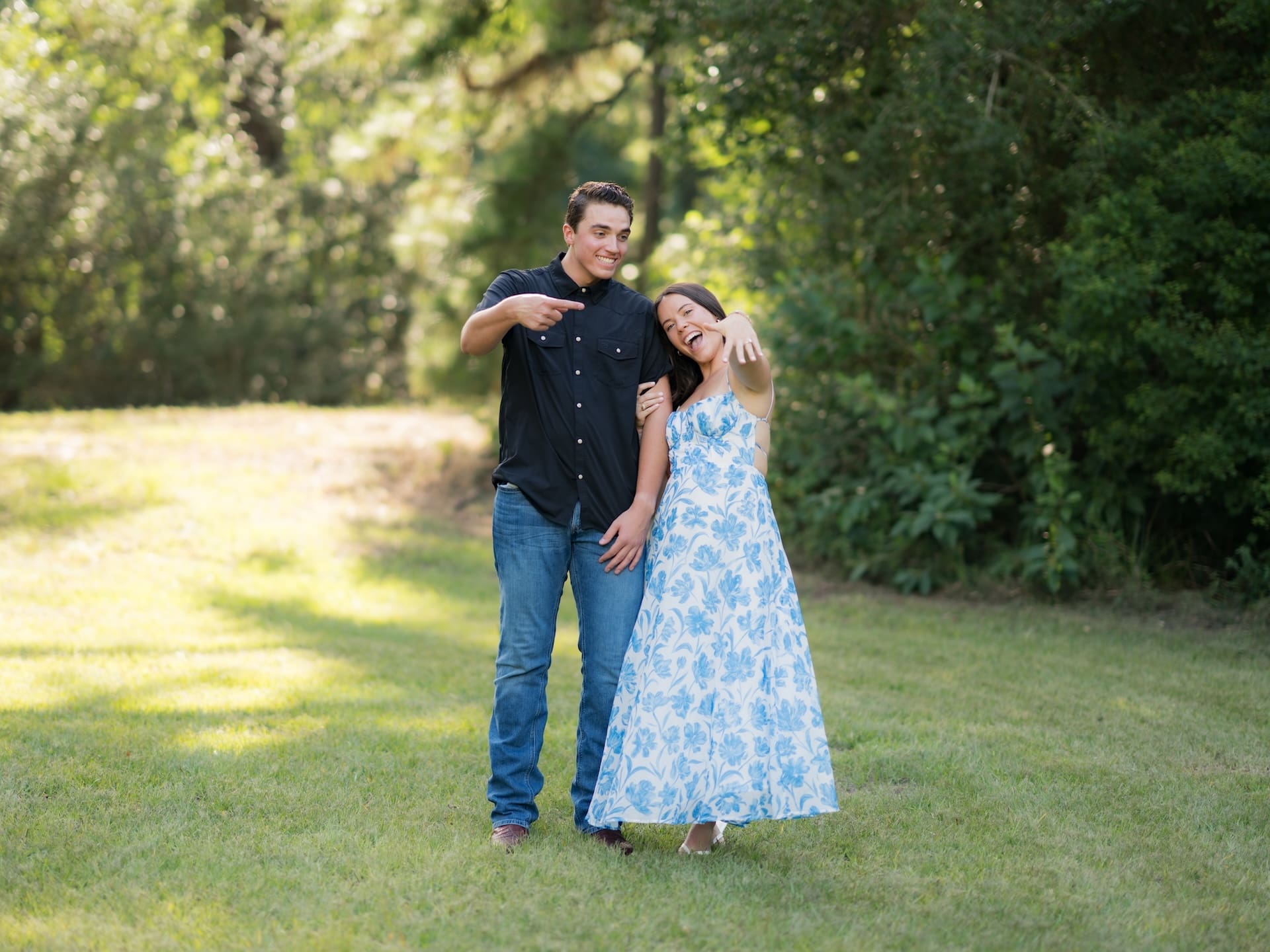 Surprise Engagement Proposal Ideas featuring a man pointing at his fiancée's new engagement ring, both laughing.