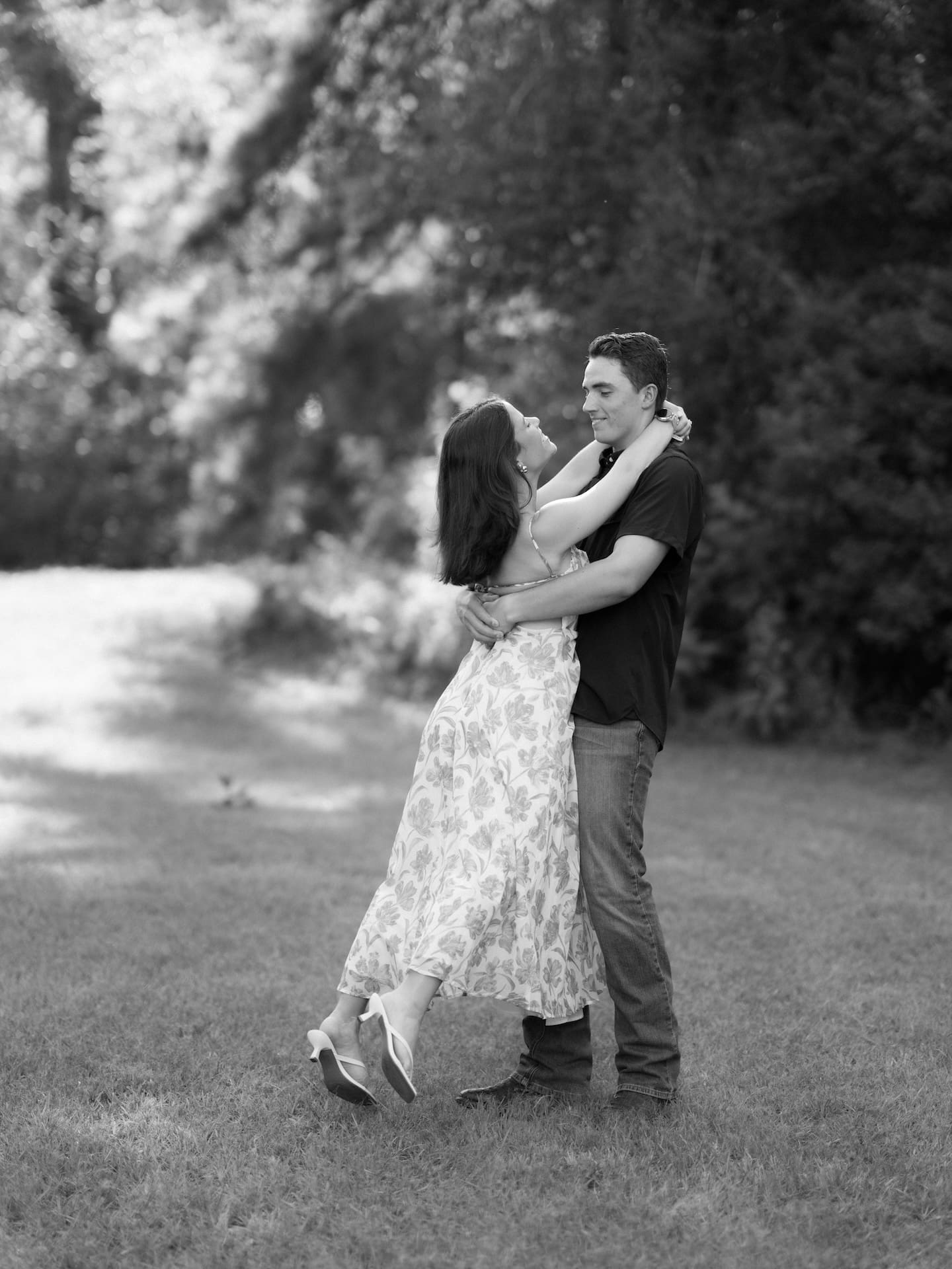 Black and white portrait of a newly engaged couple smiling closely together.