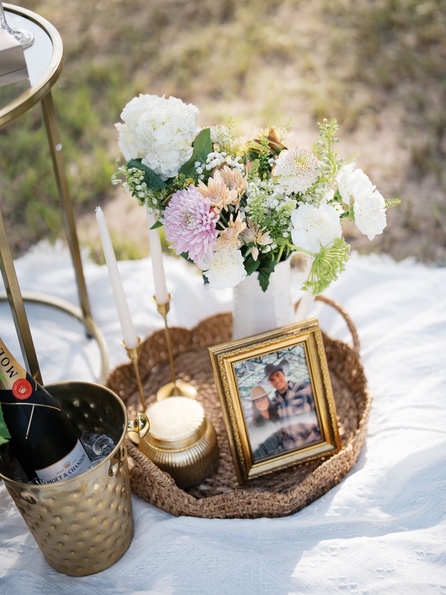 Surprise Engagement Proposal Ideas featuring a picnic setup with flowers, candles, and a framed photo.