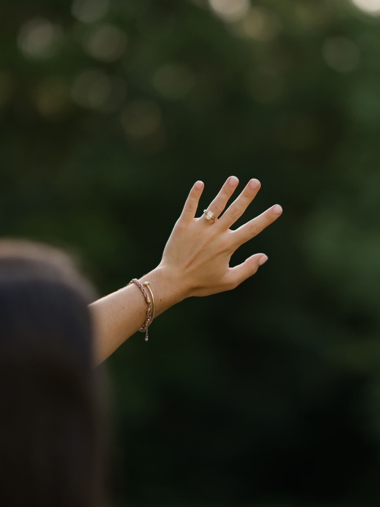 Surprise Engagement Proposal Ideas featuring a close-up of a woman's hand and engagement ring reaching upward.