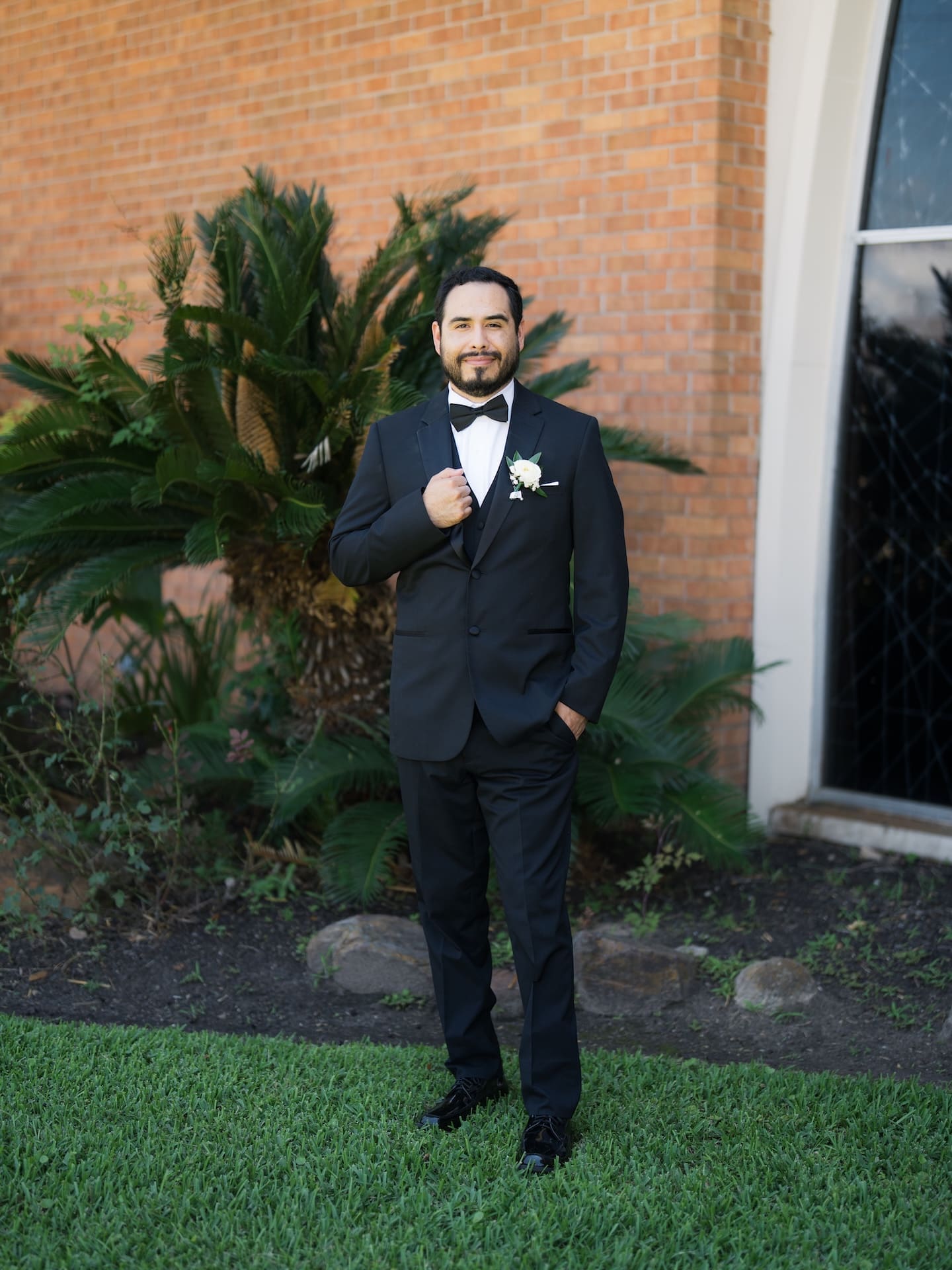 The groom standing on a manicured lawn for a luxury groom portrait.