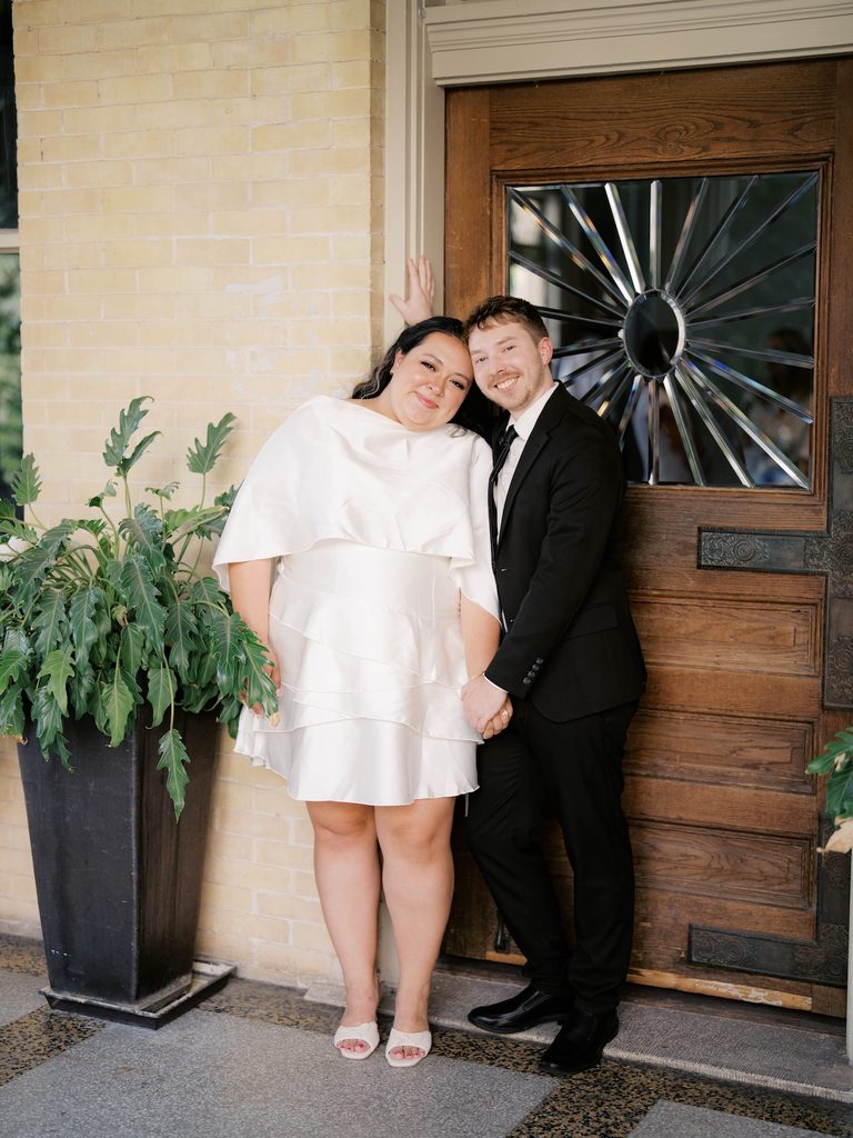 Couple leaning together in front of a historic mansion's ornate wooden door, a striking backdrop among Engagement Photo Locations.