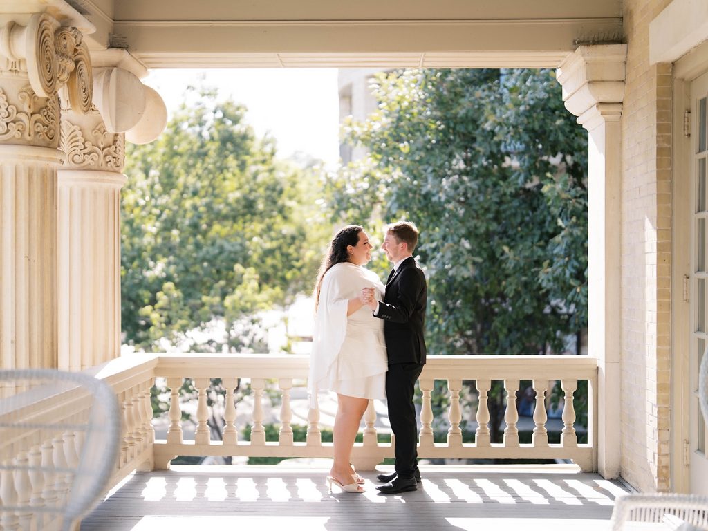 Couple sharing a slow dance on a columned balcony, one of the best Engagement Photo Locations for classic architecture and soft afternoon light.