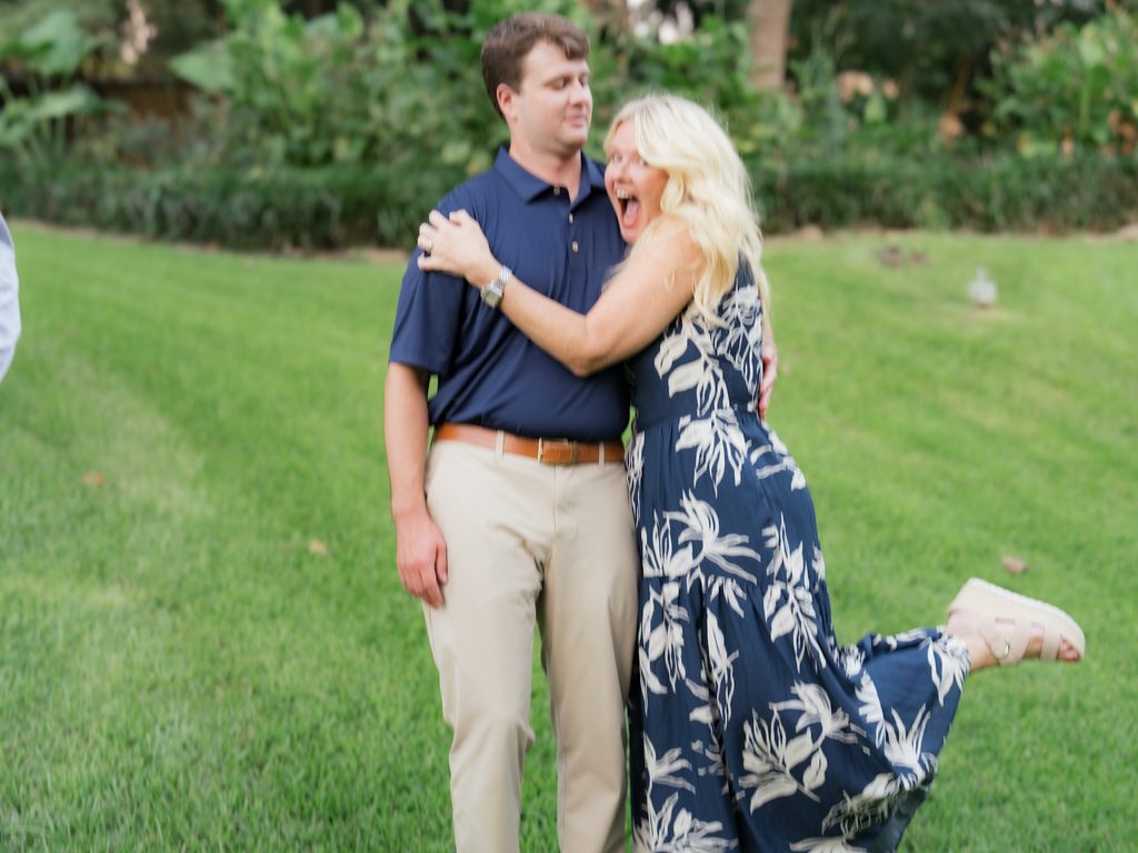 Candid, joyful moment of a guest hugging the groom-to-be and squealing with excitement at a Brenners on the Bayou proposal celebration