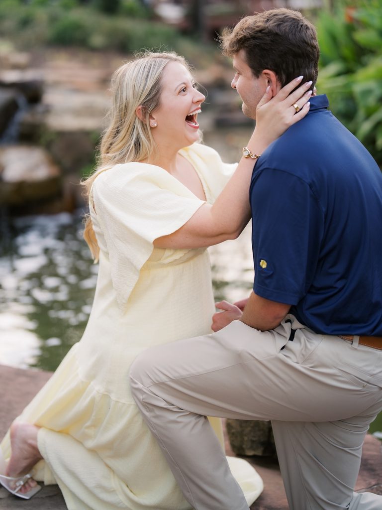 Bride-to-be reacting with pure joy and happy shock as her boyfriend kneels beside the water at a Brenners on the Bayou proposal