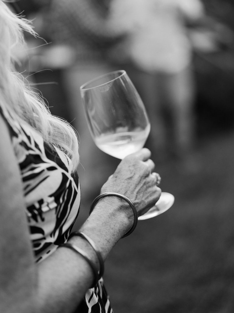 Black and white detail photo of a wine glass and gold bangles during a proposal celebration at Brenners on the Bayou in Houston